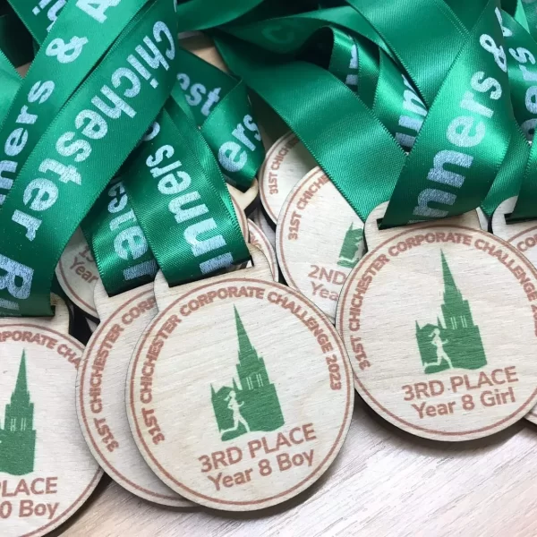 A group of wooden medals with green ribbons on them.