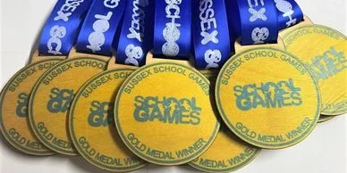Custom school games medals featuring blue ribbons.