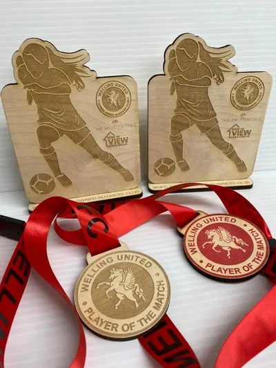 Two wooden medals with red ribbons on them, supplied by a UK Medal Supplier.