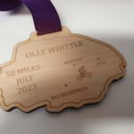 A wooden medal with the name ollie white.