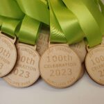 A group of wooden medals with green ribbons.