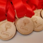 A group of wooden medals with red ribbons.