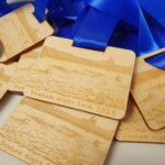 A group of wooden medals with blue ribbons.