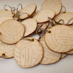 A group of wooden volleyball keychains on a white surface.