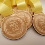 A group of wooden medals with yellow ribbons.