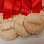 A group of wooden medals with red ribbons.