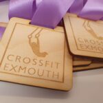 Crossfit exmouth medals with purple ribbons.