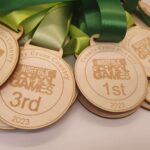 A group of wooden medals with green ribbons.