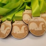 A group of wooden medals with a green ribbon.