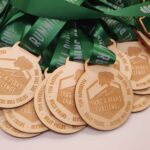 A group of wooden medals with green ribbons.