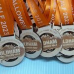 A group of race medals with orange ribbons.