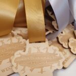 Close-up of wooden medals with gold and silver ribbons, engraved with "Geneva Cricket Cup 2024 Winner" and silhouettes of cricket players.