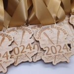 Wooden 2024 Sonning Regatta medals with gold ribbons, featuring crossed oars and a boat design.