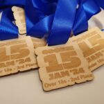 Wooden medals with blue ribbons, engraved with "COOKE JAM '24" and placements like "Under 18s - 3rd Place" and "Over 18s - 2nd Place.