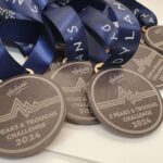 A group of round medals with blue ribbons, engraved with "Dylan's 3 Peaks & Troughs Challenge 2024.