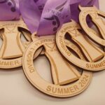 Wooden medals labeled "Division 2, 3, 5 - Player of the Season, Summer 2024" with purple ribbons.