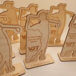 Wooden golf trophies from VJ Technology Golf Day 2024, featuring a golfer silhouette. Awards include "Winner," "Longest Drive," and "Texas Scramble Back 9.