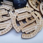 Wooden medals for the Hamro Run Club Half Marathon Relay 2024 are stacked, each featuring the text "Running to Inspire.