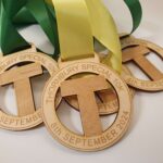 Three wooden medals with green and yellow ribbons, inscribed with "Thornbury Special 10K" and the date "8th September 2024.