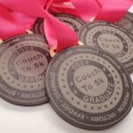 A collection of round medals with pink ribbons, labeled Couch to 5k Graduate 2024. The medals feature words like Discipline, Respect, Honour, Courage, Pride, and Effort around the edges.