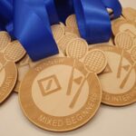 A collection of wooden medals with blue ribbons, engraved with tennis rackets and the words Winner and Mixed Beginners.