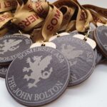 A collection of medals with brown ribbons, each featuring a design of a griffin and the words Somerset ASA and The John Bolton.