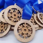 A pile of wooden medals with engraved snowflakes, labeled Winter Throwdown and various placements like 1st Place and 2nd Place, connected by blue ribbons.