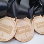 Close-up of CrossFit Beowulf medals with black ribbons, featuring CrossFit Beowulf 2024 RX Division text. The medals are stacked, displaying third, second, and first place engravings.