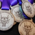 A pile of wooden medals with a dragon design and the text Bracknell Ice Skating Club, Student of the Month. Each medal has a purple ribbon attached.